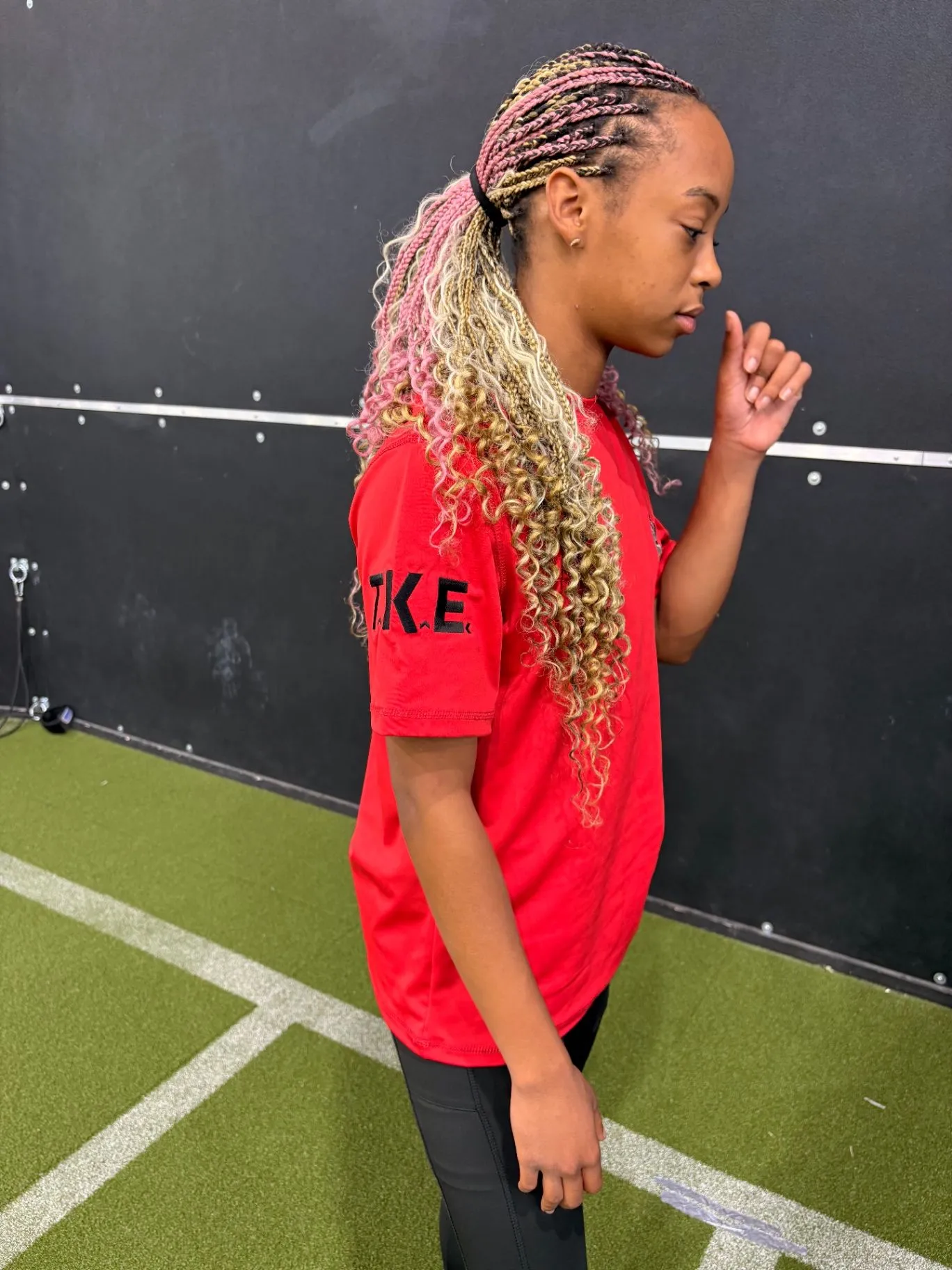 Nailah Belcher walking through an indoor training facility in a red shirt