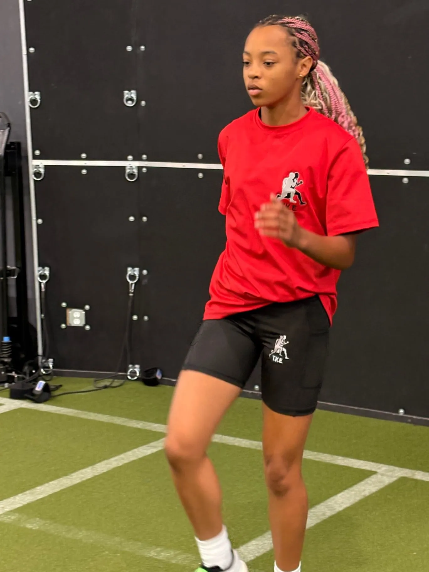 Nailah Belcher running an indoor training drill in a red team shirt